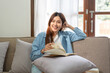 © Katcha - Young woman is reading a book or literature while sitting on comfortable the couch to relaxing