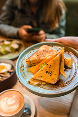 Wall Mural - Brunch in cafe. Close-up toast and cup of coffee on the table. Woman having healthy breakfast