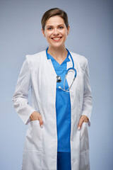 Wall Mural - Isolated portrait og smiling woman doctor with hands in pockets in white coat.