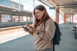 © Shi  - Young redhead woman with passport waiting on station platform and using smart phone. Railroad transport concept. Travel to vacation by fast train.