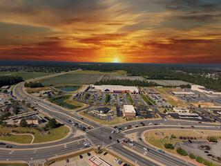 an aerial shot of the city of Warner Robins Georgia with vast miles of lush green trees, grass and plants with buildings and highways with cars driving and powerful clouds at sunset