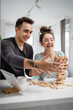 © Miljan Živković - young couple woman and man play jenga game at home on the table