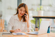 © ArLawKa - Asian women use smartphones and laptops to do financial accounting work in the office.