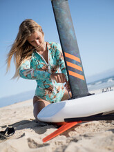Caucasian Young Woman On The Beach Setting Up Hydrofoil Surfboard