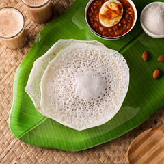 Poster - Appam, Kerala breakfast food egg curry or hot and spicy chickpea Masala and milk tea chai, Christian breakfast on dark black background. fermented rice pan cake. Top view of Indian veg food.