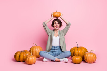 Canvas Print - Full body photo of impressed attractive girl sit hold pumpkin above head isolated on pink color background