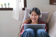 © wichayada - Attractive smiling young woman using tablet and listen music on sofa at home. lifestyle concept.