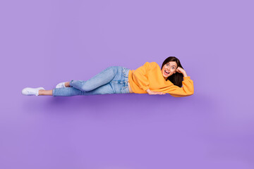 Wall Mural - Full length photo of astonished person superhero lying air dressed orange autumn trendy sweater isolated on purple color background