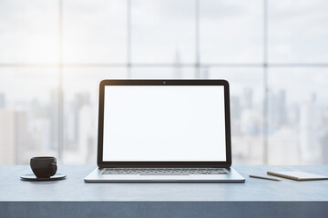 Poster - Close up of empty white notebook computer on concrete desktop with coffee cup, notepad, pen, mock up place on screen, blurry office interior with window and city view background. 3D Rendering.