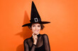 Photo portrait of cute young girl bite lip flirting tempting look dressed trendy black halloween witch outfit isolated on orange background