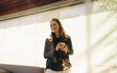 Happy senior woman holding a cup of tea in her living room