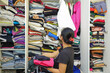Shopaholic asian woman.  Organized little walk in wardrobe with clothes and linen storage boxes.  Full walk in closet with clothes piled and hanging and a set of shoes under near the laundry basket.