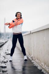 Wall Mural - Woman stretching before running on the bridge at winter and snow.