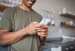 © N Lawrenson/peopleimages.com - Hands, phone and man texting in a kitchen, relax and smile while reading social media message. Internet, communication and guy planning fun vacation day, streaming and enjoying online app in his home