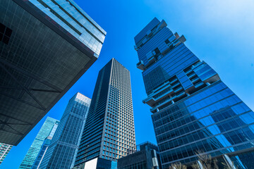 Wall Mural - Bottom view of modern skyscrapers in business district against blue sky