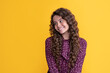 cheerful child with long brunette frizz hair on yellow background