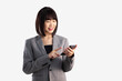 © CREATIVE WONDER - Asian business woman short hair wear grey suit using and touching screen smartphone on white background.