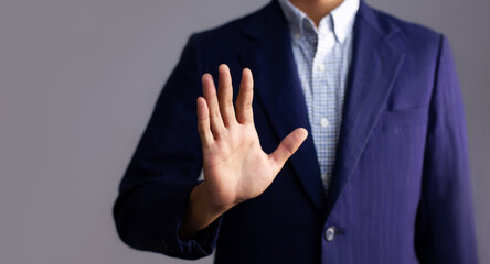 Poster - Young asian businessman in dark blue jacket posing hand touching on gray background.