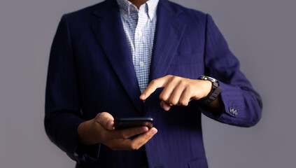 Poster - Young asian businessman in dark blue jacket suit holding smartphone finger pointing and touching on smartphone.