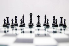 Of Black Chess Pieces On A Reflective Chessboard On White Background