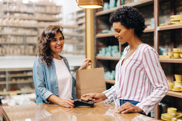 Happy shop owner scanning a credit card in her ceramic store