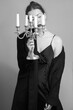 Vertical greyscale shot of an attractive female posing with a candleholder