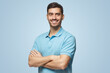 © Damir Khabirov - Smiling handsome young man in polo shirt standing with crossed arms, isolated on blue background