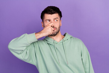 Sticker - Portrait photo of young funny unhappy student man wear khaki sweater close his nose smell stink look empty space object isolated on violet color background