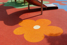 Red, Orange And Yellow Padded Granular Soft Rubber Safety And Sports Floor. Play Surface. Kids Playground. Leisure, Play, Outdoors And Sports Activity Concept. Flower Pattern. Protective Flooring.