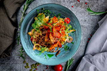 Wall Mural - Green salad with fried potato chips, tomatoes, mushrooms and beef with red onion rings and arugula