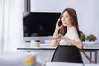 © David - Freelance Smiling young asian business woman using computer laptop working at home Office, Happy business asian woman talking on mobile phone while analyzing weekly schedule in her notebook.