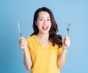 Wall Mural - Image of young Asian woman holding knife and fork