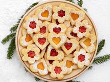 Linzer Cookies In A Shape Of Hearts And Flowers Filled With Strawberry And Apricot Jam, Spruce Twig Around Plate