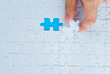 © xy - Hand putting the last piece of white jigsaw puzzle
