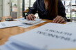 © Natee Meepian - Accountant woman working on desk office with using a calculator to calculate the numbers, finance accounting concept