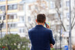 © Oleg - Short haired man in a business suit talking on mobile phone on a city street. Concept of cellular communication