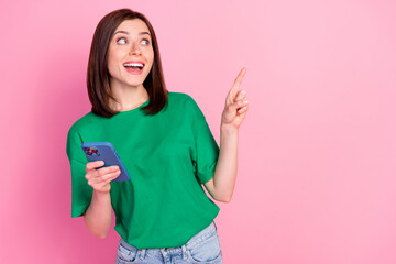 Wall Mural - photo of excited positive lady look direct finger empty space hold telephone isolated on pink color 