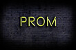 Neon sign. Word prom against brick wall. Night view