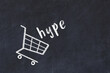 © iushakovsky - Chalk drawing of shopping cart and word hype on black chalboard. Concept of globalization and mass consuming
