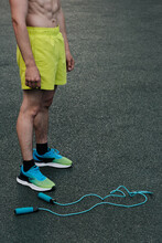 Vertical Shot Of Unrecognizable Muscular Man Wearing Stylish Yellow Shorts And Training Shoes Standing With Jump Rope On Ground