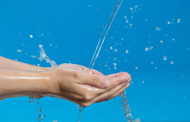 Wall Mural - Woman hands catching water on blue background