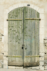 Wall Mural - Green shabby wooden gate in natural stone wall