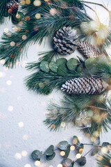 Wall Mural - christmas nature card with pine branches and fir cones on white background with magic bokeh lights -