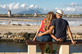 Fototapeta Londyn - Young couple in love embracing contemplating the beauty of Salt flats in Sicily Italy
