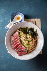 Wall Mural - Tuna steak ramen. Japanese soup with noodles ramen, miso, fried tuna steak and seaweed algae. Top view. blue background.