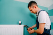 © Ruslan Ivantsov - Repair heating radiator close-up. man repairing radiator with wrench.