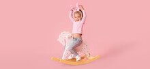 Adorable Little Girl Playing With Rocking Horse On Pink Background