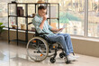 © Pixel-Shot - Young man with physical disability working in office