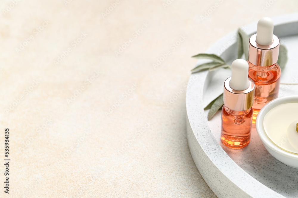 Board with bottles of essential olive oil on light background