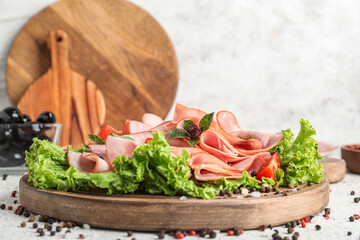 Wall Mural - Wooden board with sliced ham, lettuce and spices on light table, closeup